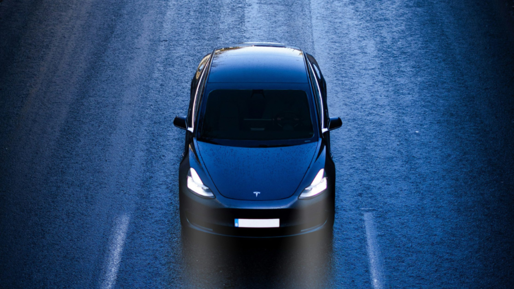 Tesla nera su strada vista dall'alto e frontale, in scherse condizioni di luminosità