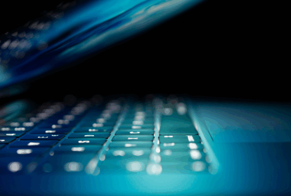 Tastiera retroilluminata di un laptop con schermo semiaperto, simbolo della tecnologia no-code e low-code per lo sviluppo software senza programmazione